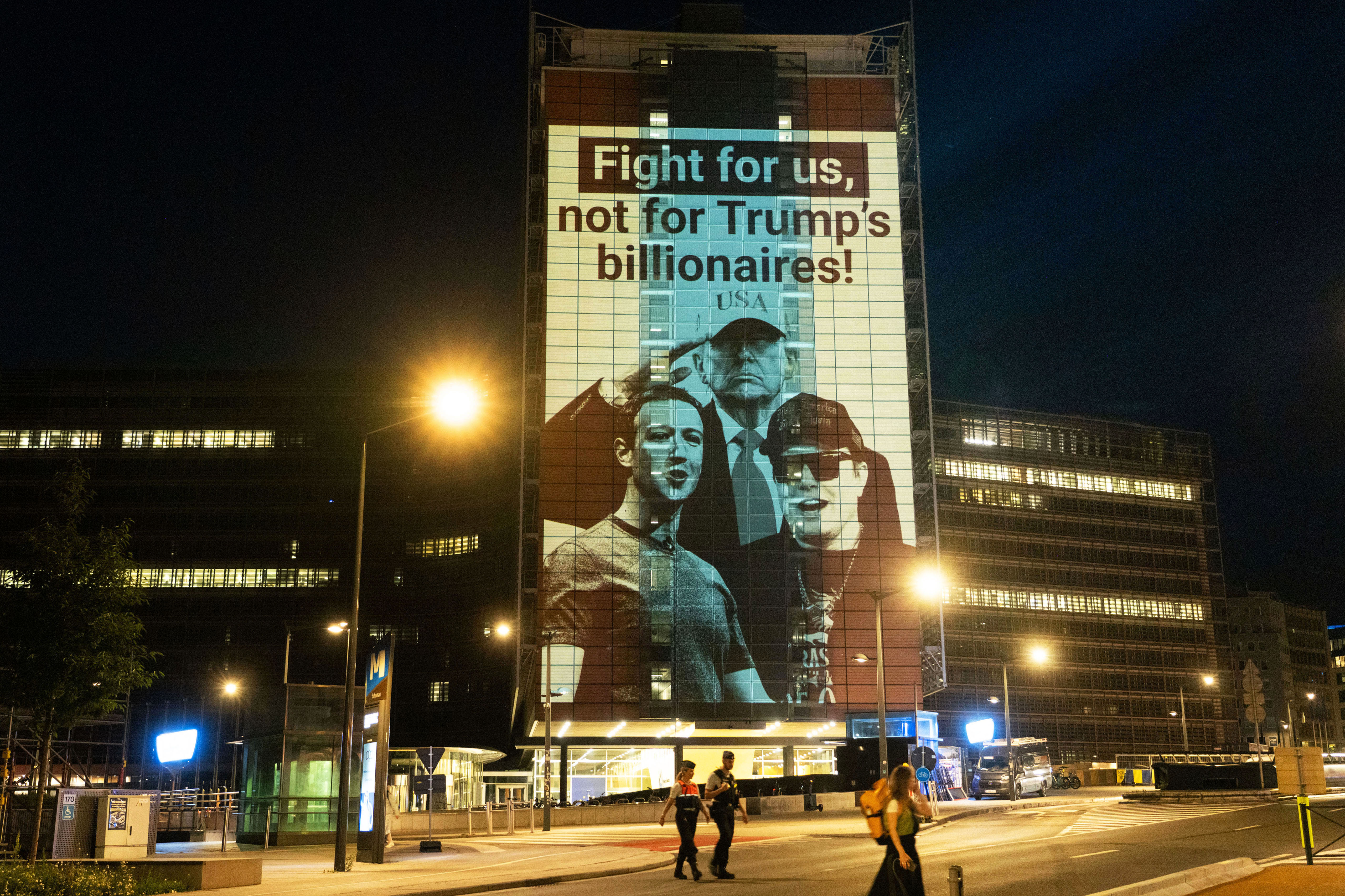 Una proyección con imágenes de Trump, Musk y Zuckerberg sobre un edificio de la UE, con el mensaje: "Defiendan a la ciudadanía, no a los multimillonarios de Trump".